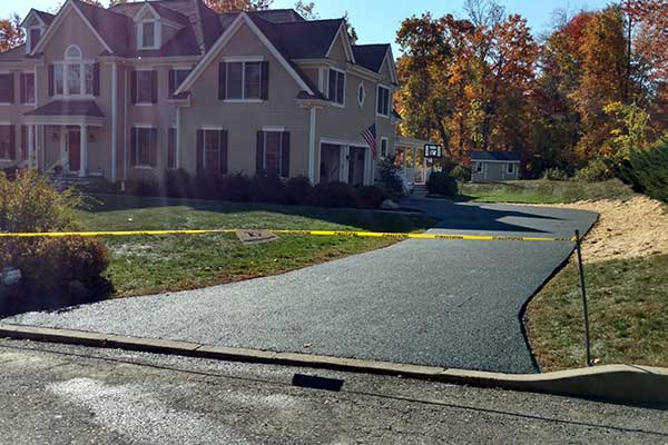 A house with a newly paved driveway. A sign for Tom Quartuccio Jr, LLC hangs at the entrance