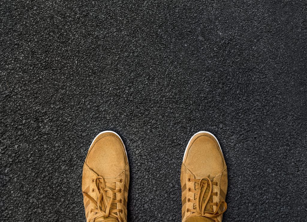 Two yellow boots standing on fresh asphalt