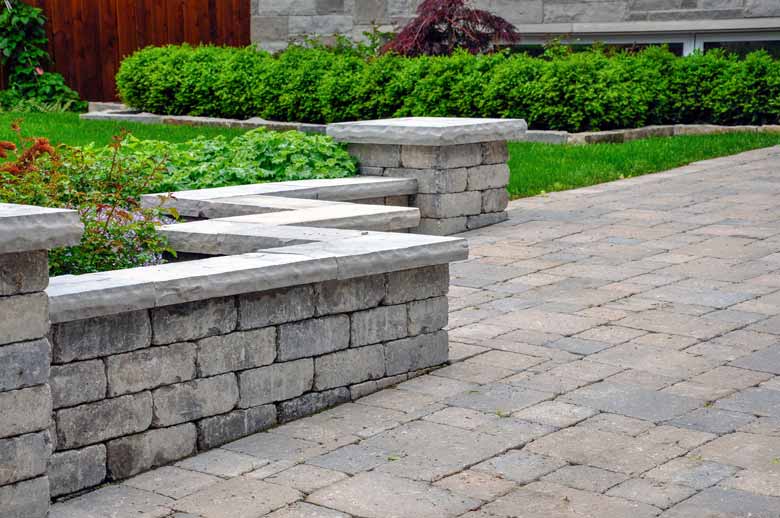 A walkway paved with stone blocks with a stone retaining wall running along one side