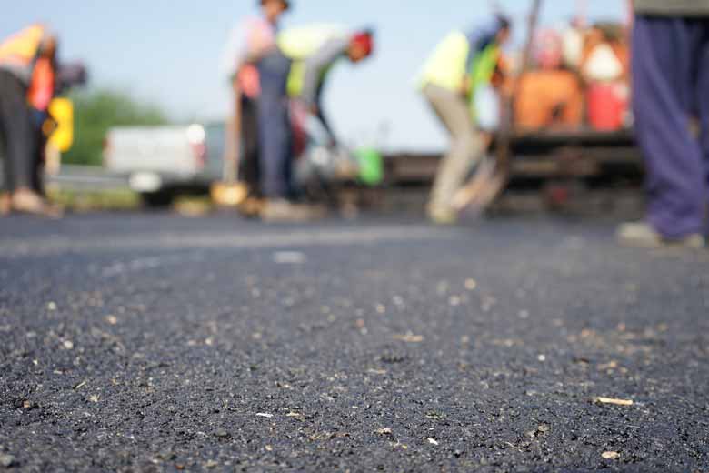 A crew of men paving an asphalt driveway